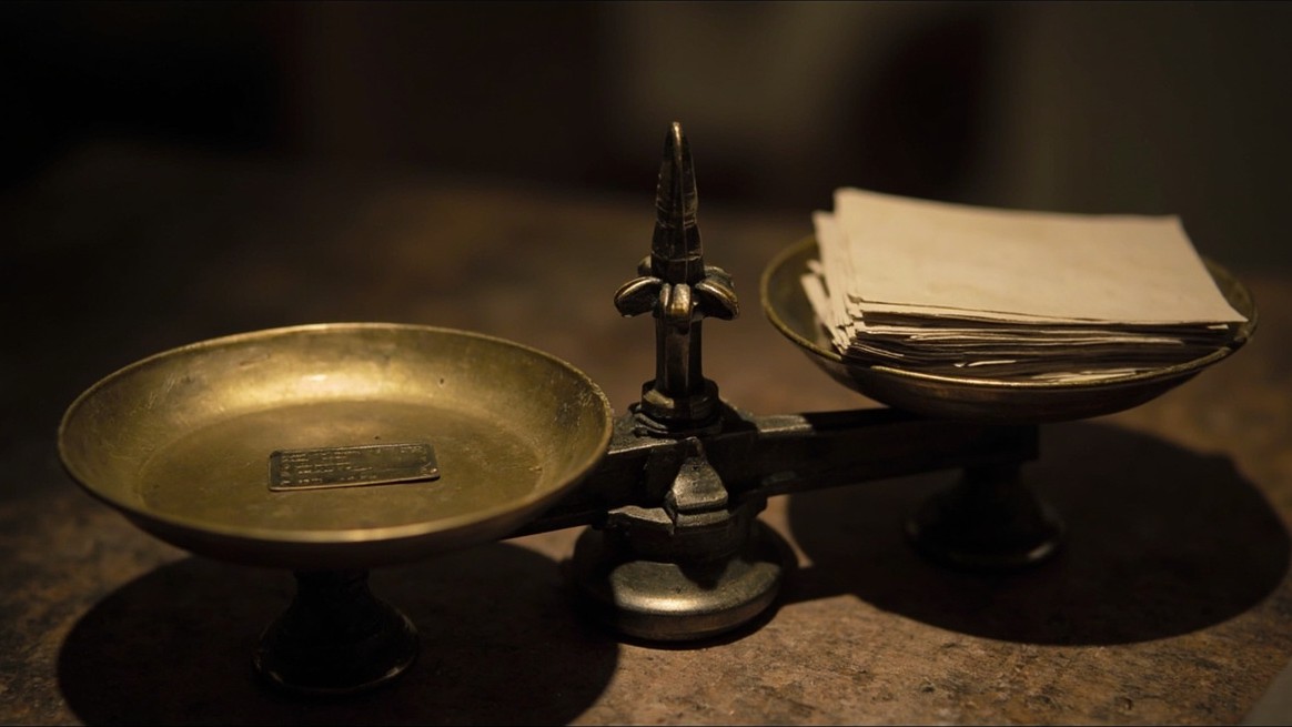 Brass scales weighing one heavy tag against a stack of thin paper cards