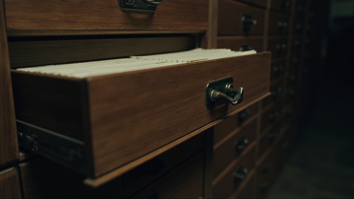 A library card-catalogue cabinet with one drawer open showing index cards
